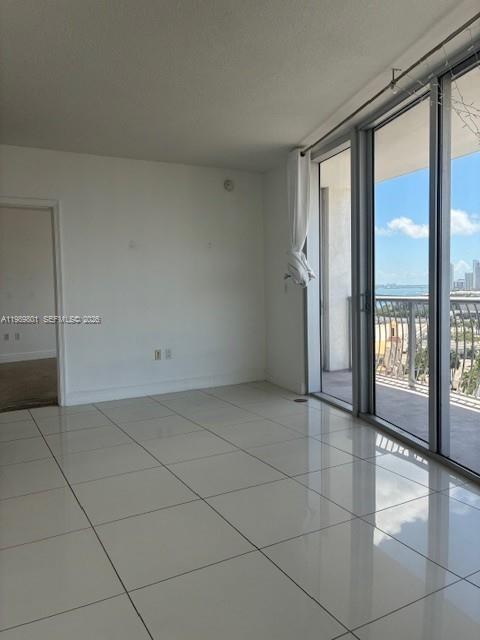 An empty room with white tile floors, white walls, and a sliding glass door balcony — 1750 N Bayshore Dr # 1714, Miami FL 33132, MIAMI, FL