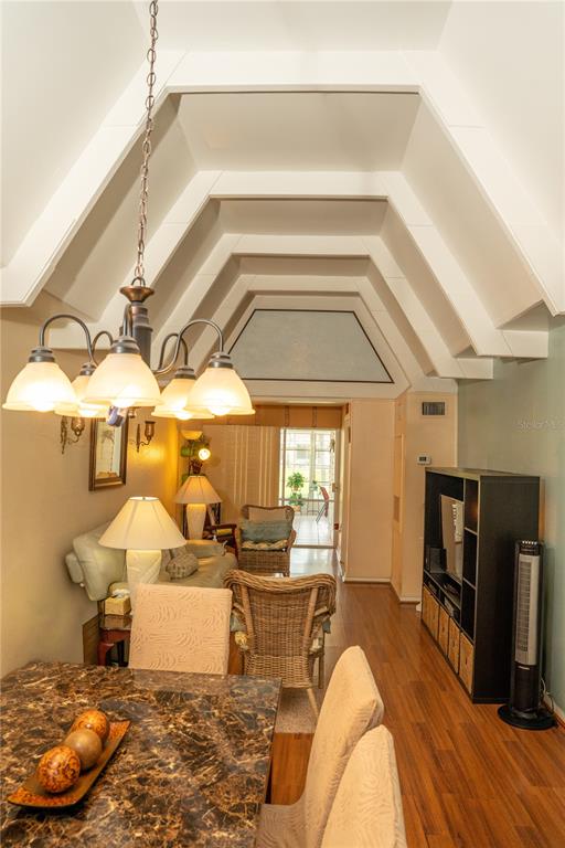 A dining area with a marble table leads into a living room with vaulted ceilings — 1511 CLUB CIRCLE, LAKE WALES, FL