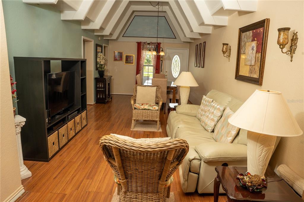 A living room features wood flooring, a vaulted ceiling, a sofa, and wicker armchairs — 1511 CLUB CIRCLE, LAKE WALES, FL