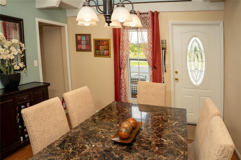 A dining room features a marble-topped table, upholstered chairs, a chandelier, and a front door — 1511 CLUB CIRCLE, LAKE WALES, FL
