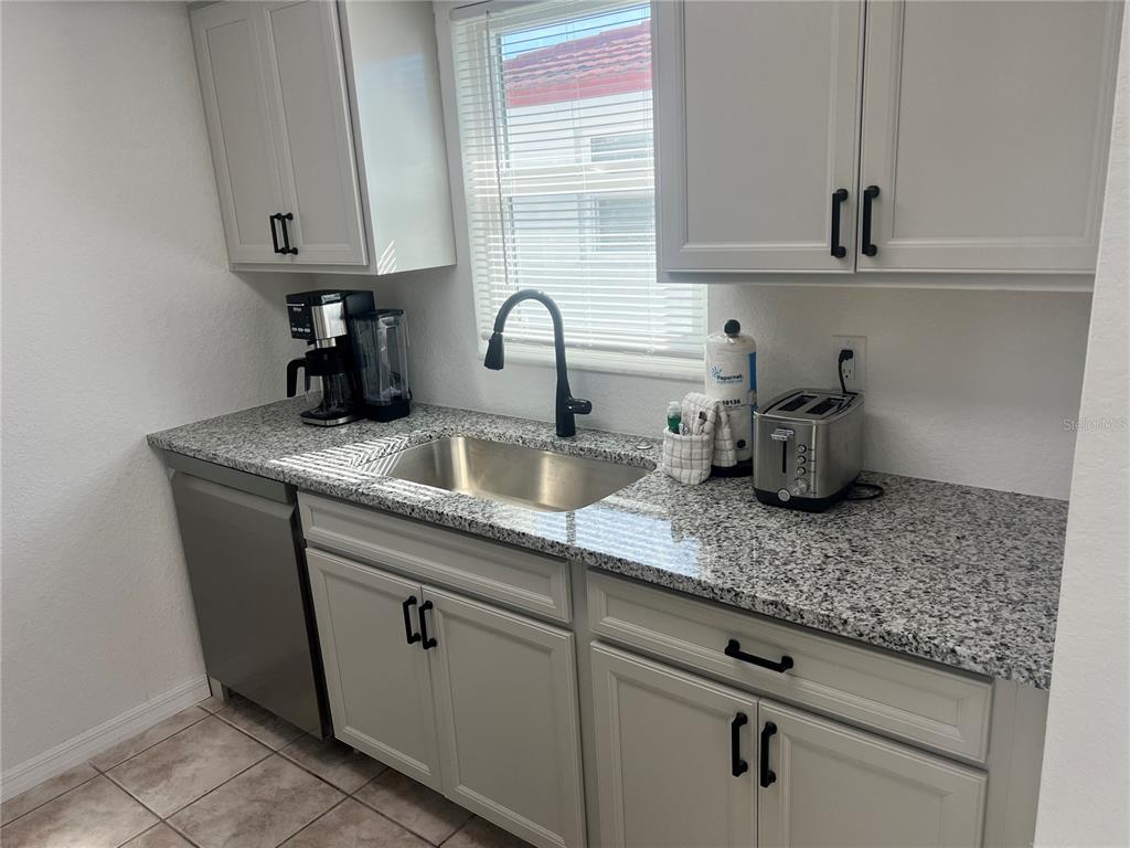A kitchen features light gray cabinets, granite countertops, a stainless steel sink, and a dishwasher — 6154 MIDNIGHT PASS ROAD UNIT B03, SARASOTA, FL