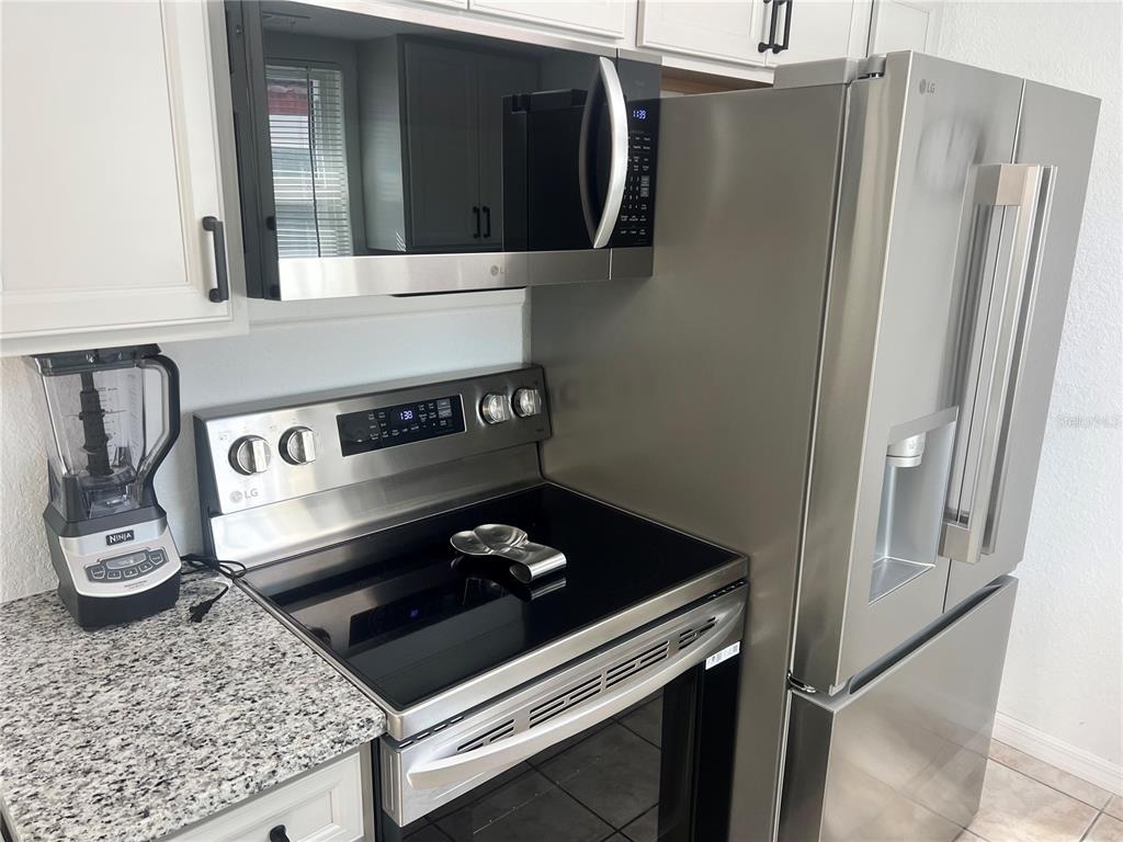 A kitchen features stainless steel appliances, white cabinets, and granite countertops — 6154 MIDNIGHT PASS ROAD UNIT B03, SARASOTA, FL