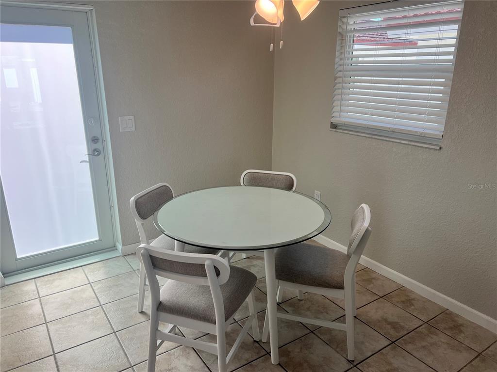 A dining area features a round glass table with four chairs on a tiled floor — 6154 MIDNIGHT PASS ROAD UNIT B03, SARASOTA, FL