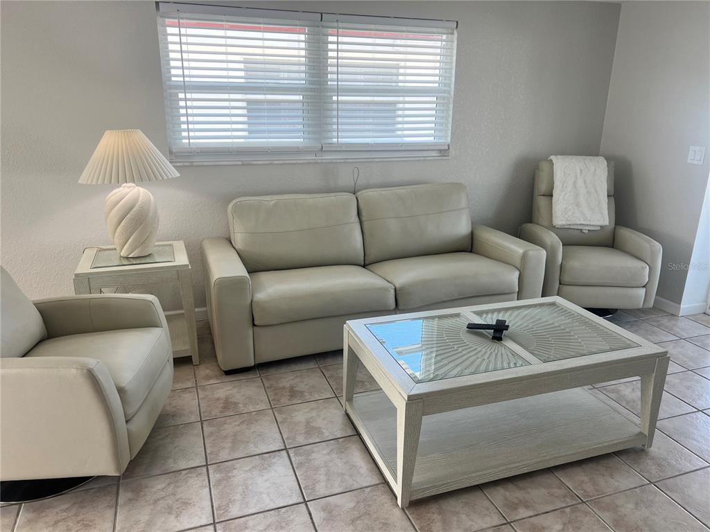 A living room features a light-colored sofa, two armchairs, a glass-topped coffee table, and tile flooring — 6154 MIDNIGHT PASS ROAD UNIT B03, SARASOTA, FL