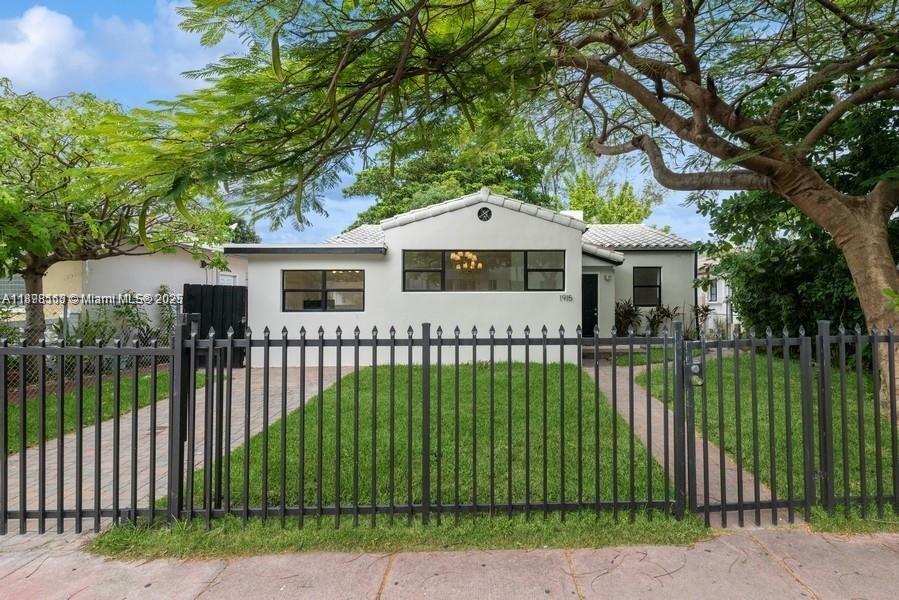 A single-story white house with a black metal fence and a paved driveway — 1915 Normandy Drive, Miami Beach FL 33141, MIAMI BEACH, FL