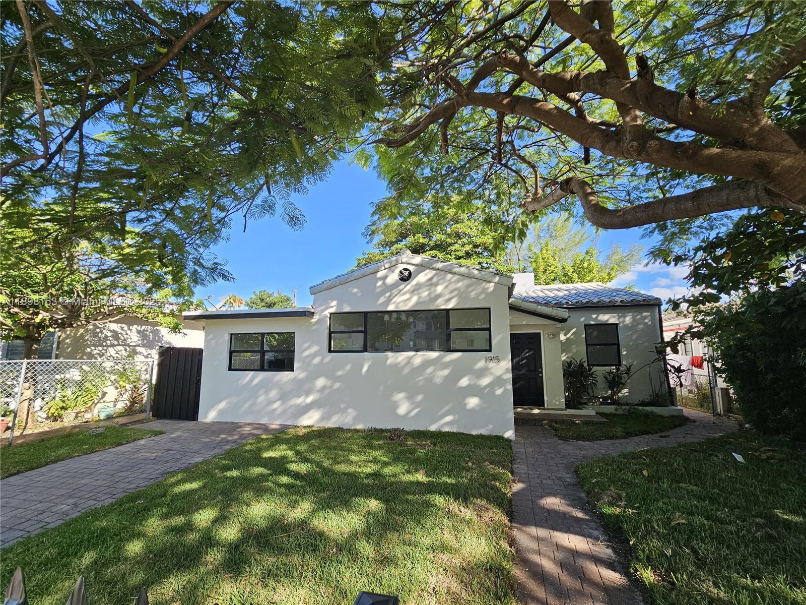 A single-story white house with a tiled roof sits behind a brick walkway and lawn — 1915 Normandy Drive, Miami Beach FL 33141, MIAMI BEACH, FL
