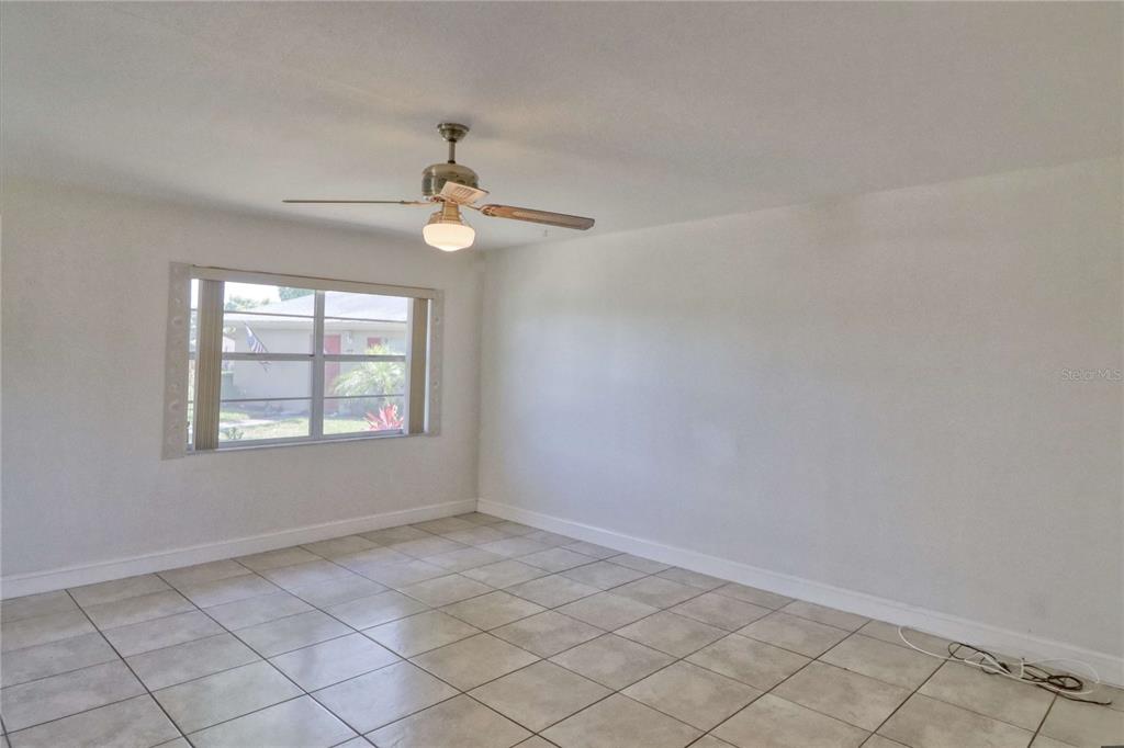 An empty room features white walls, light-colored tile flooring, and a ceiling fan with light — 302 CANTON COURT UNIT 59, SUN CITY CENTER, FL
