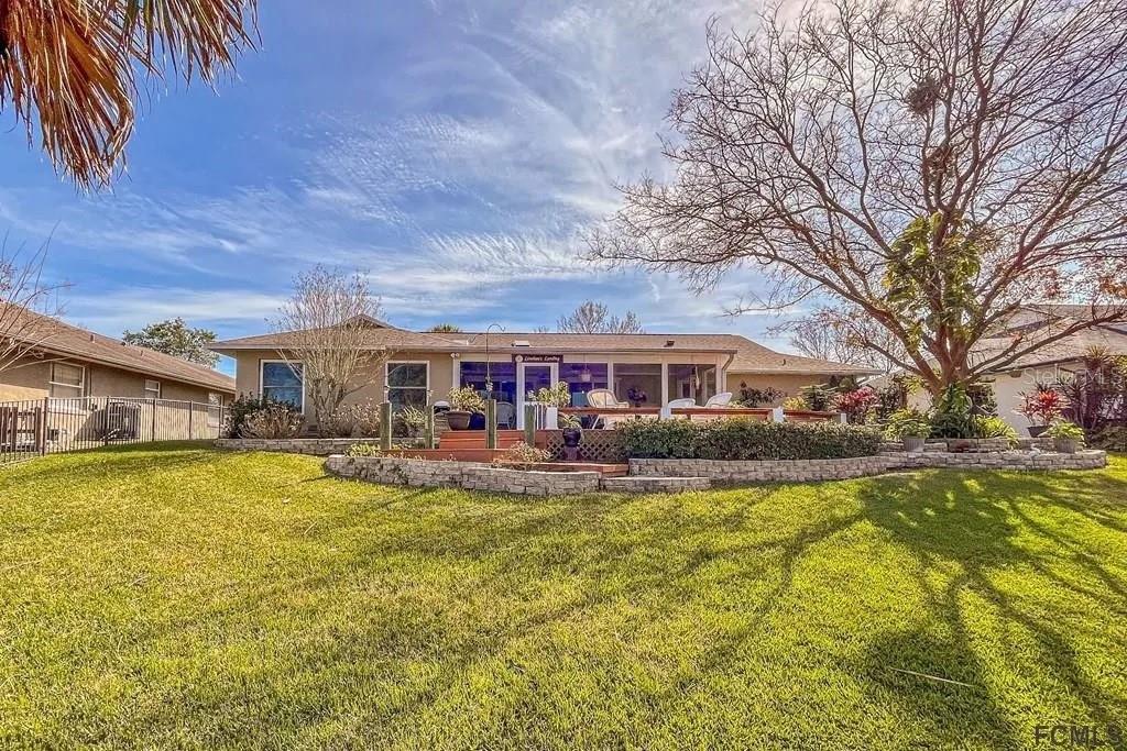 A single-story house with a screened porch and a stone retaining wall in the backyard — 13 CEDARFORD COURT, PALM COAST, FL