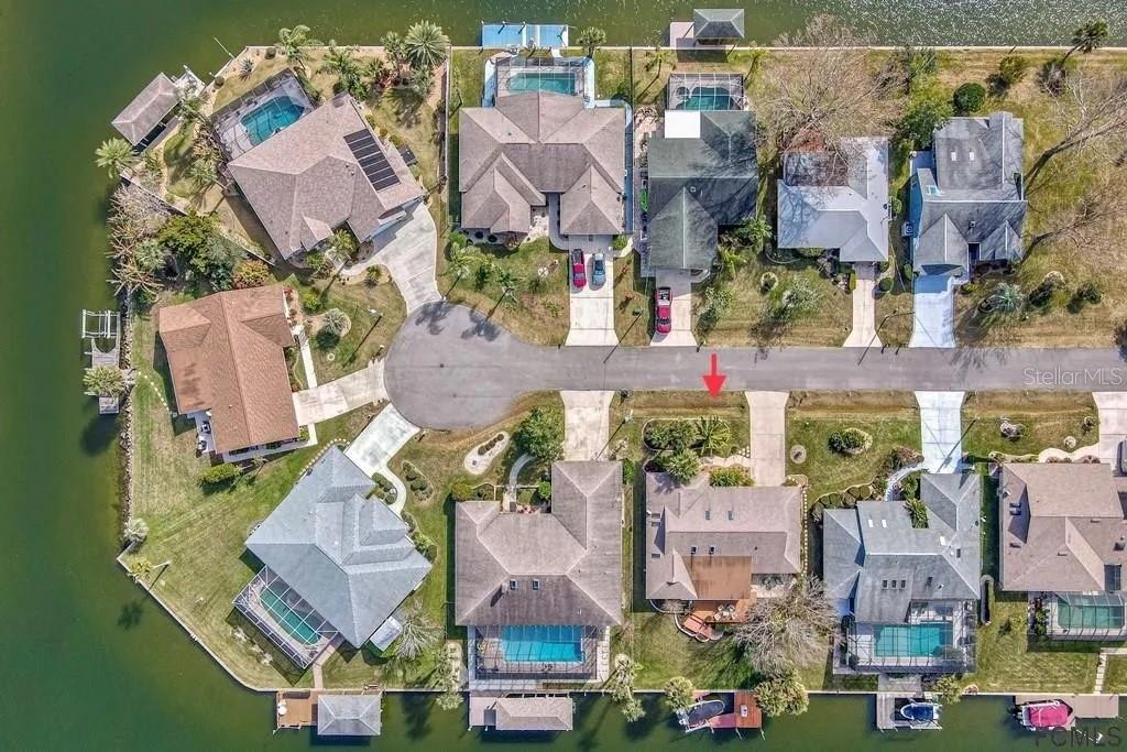 An aerial view shows a residential cul-de-sac with waterfront homes, swimming pools, and driveways — 13 CEDARFORD COURT, PALM COAST, FL