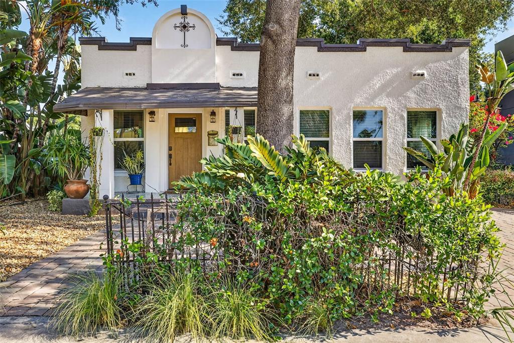 A white stucco house with a mission-style parapet, wooden door, and a front garden — 2705 N POPLAR AVENUE, TAMPA, FL