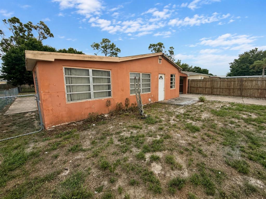The exterior of a single-story orange house with a fenced yard and a concrete patio — 48 PRINCETON AVENUE, FROSTPROOF, FL