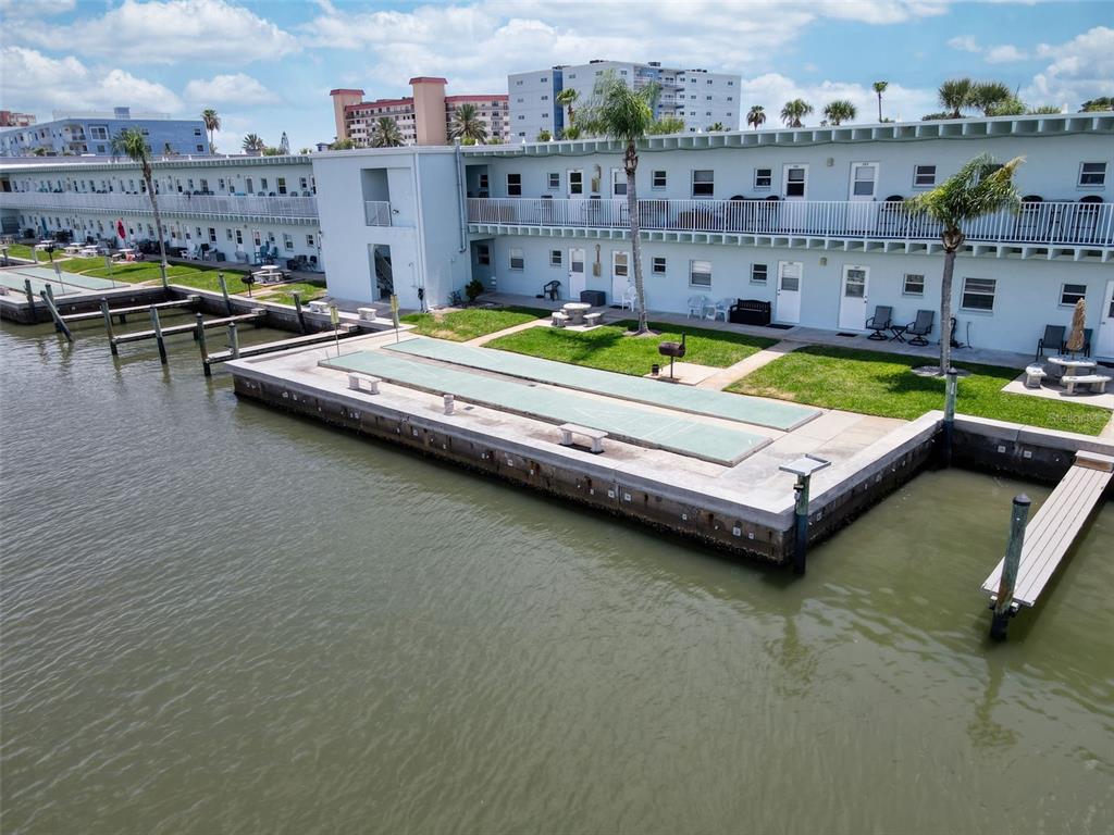An aerial view shows a waterfront apartment building with shuffleboard courts on a concrete patio — 18399 GULF BOULEVARD UNIT 364, INDIAN ROCKS BEACH, FL