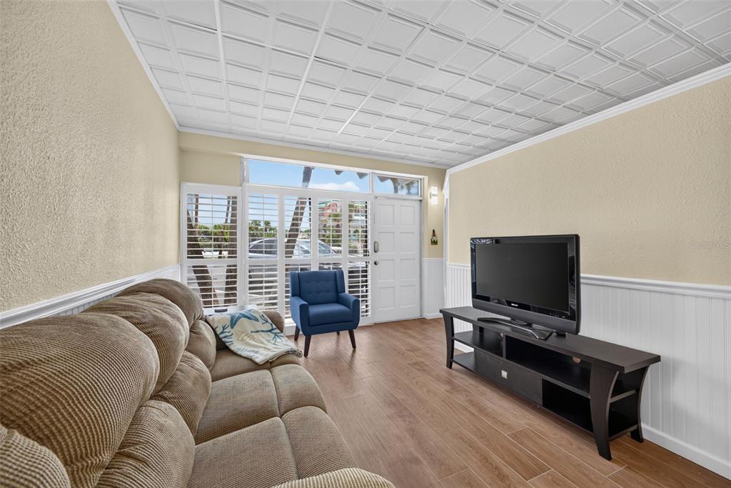 A living room features a brown sofa, a blue armchair, a television, and tile flooring — 18399 GULF BOULEVARD UNIT 364, INDIAN ROCKS BEACH, FL