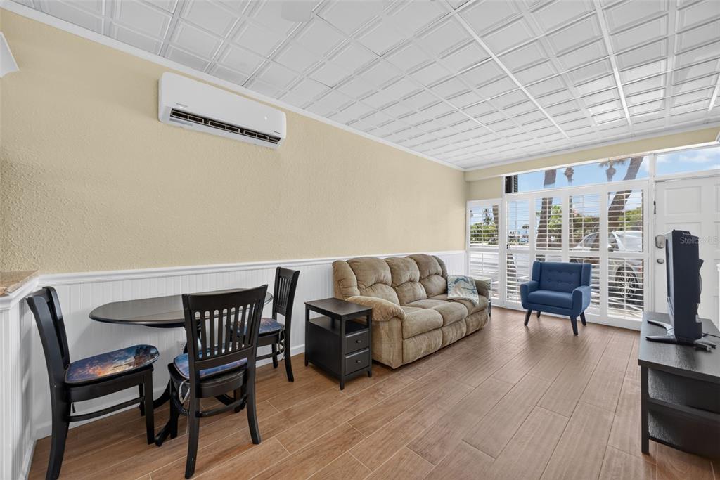 A living and dining area features a tan sofa, blue armchair, and wood-look tile flooring — 18399 GULF BOULEVARD UNIT 364, INDIAN ROCKS BEACH, FL