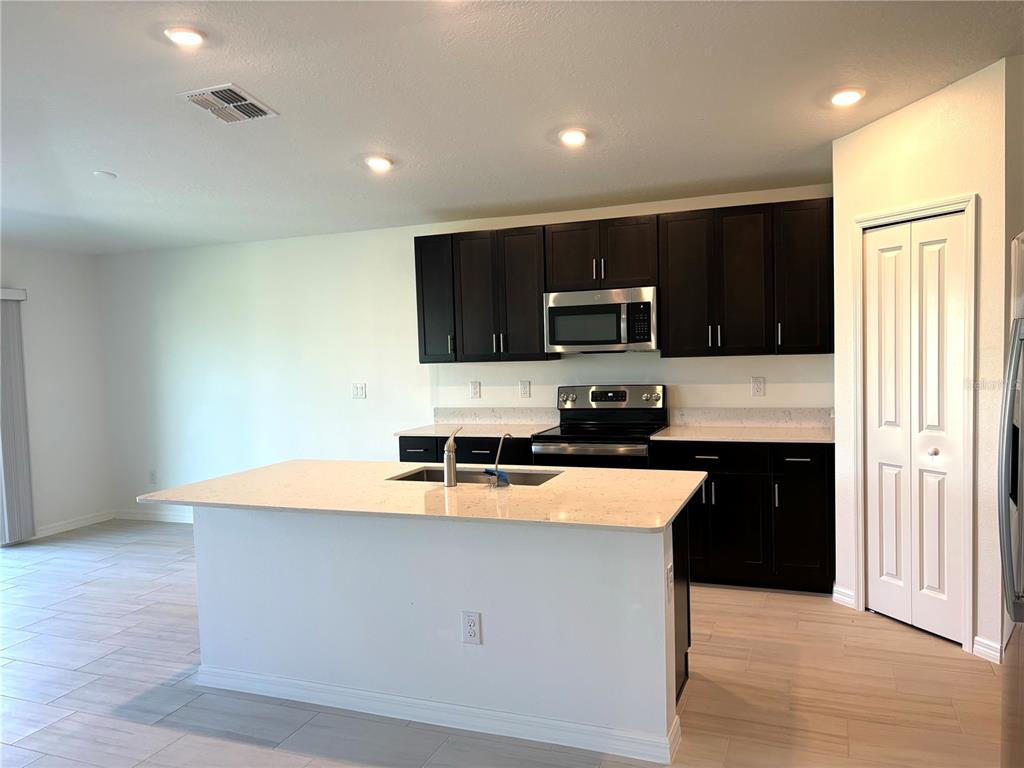 A kitchen features dark wood cabinets, white quartz countertops, a center island, and tile flooring — 3615 NATURAL TRACE STREET, PLANT CITY, FL