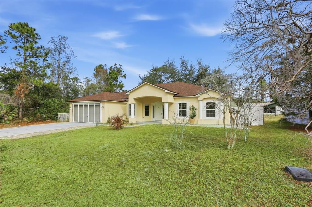 A single-story house with a tan exterior, brown roof, and a paved driveway — 78 PANORAMA, PALM COAST, FL