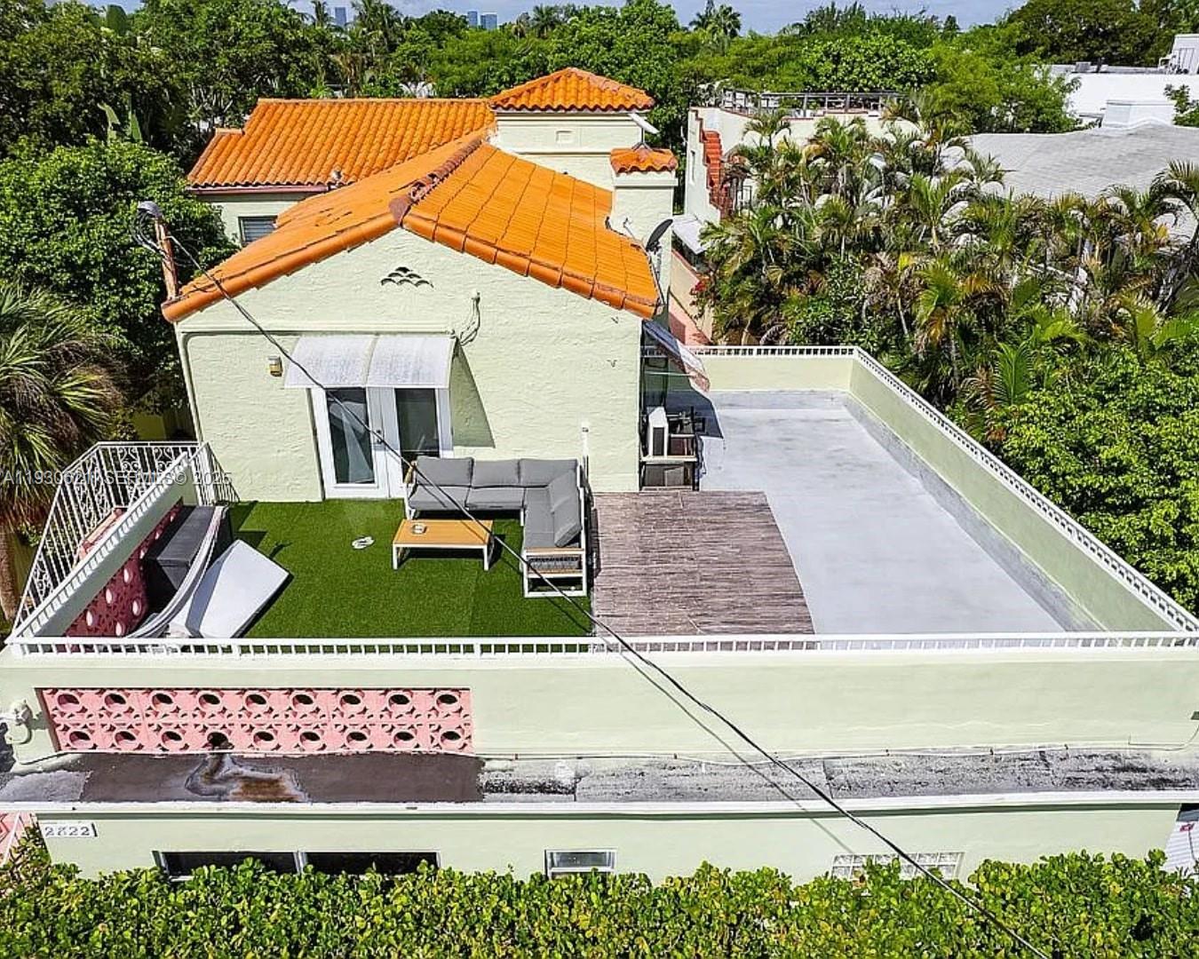 An aerial view of a house rooftop featuring a patio with artificial turf and decking — 2822 Pine Tree Dr, Miami Beach FL 33140, MIAMI BEACH, FL