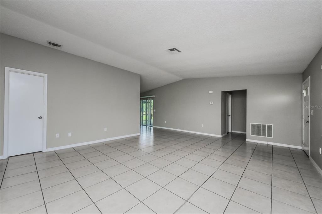 An empty room with light gray walls, white trim, and large square floor tiles — 211 COBALT DRIVE, KISSIMMEE, FL