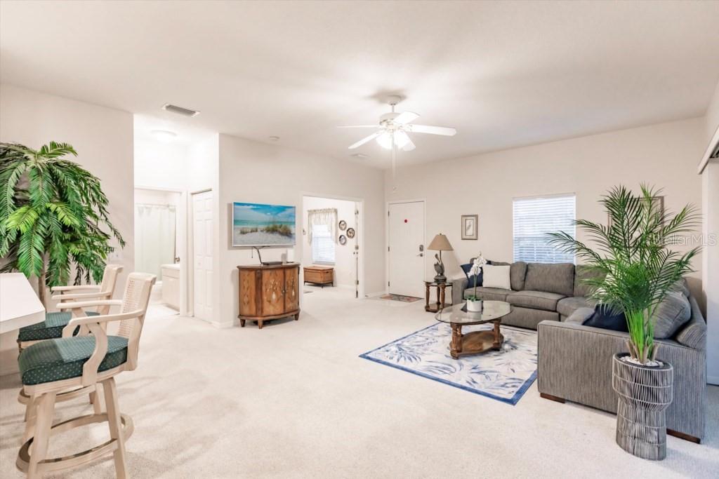 A living room features light carpeting, a grey sectional sofa, and a ceiling fan — 1337 RED OAK LANE, PORT CHARLOTTE, FL
