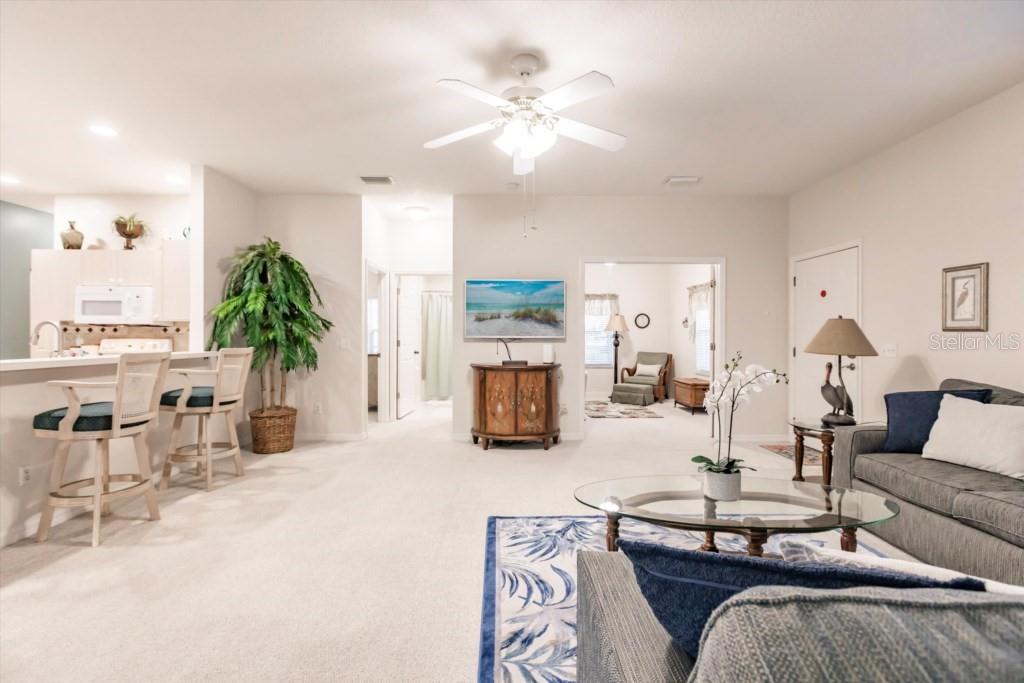 A living room with light carpet, a ceiling fan, and a view into an adjacent room — 1337 RED OAK LANE, PORT CHARLOTTE, FL