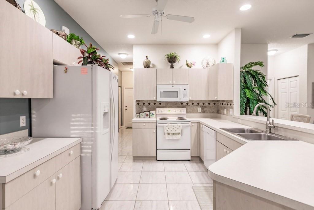 A kitchen with light wood cabinets, white appliances, tile flooring, and a peninsula sink — 1337 RED OAK LANE, PORT CHARLOTTE, FL