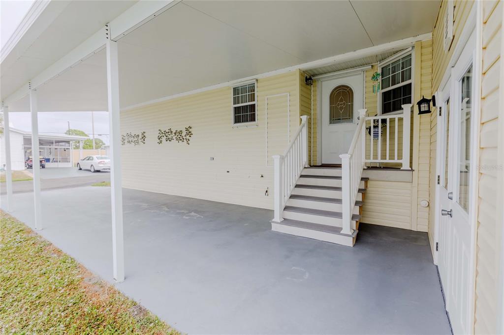 A covered carport leads to a set of stairs and a white front door — 2100 KINGS HIGHWAY UNIT 200, PORT CHARLOTTE, FL