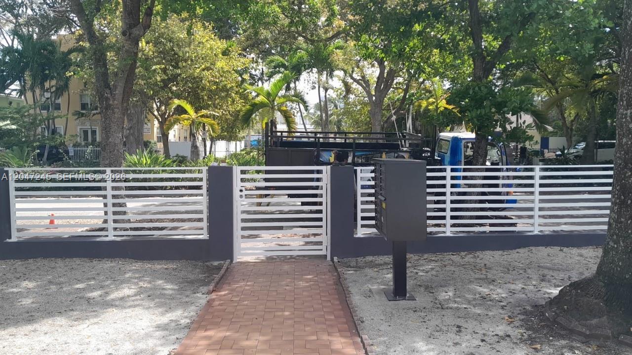 A white horizontal slat fence and gate enclose a paved walkway leading to a mailbox — 852 SW 13th Ave # 3, Miami FL 33135, MIAMI, FL