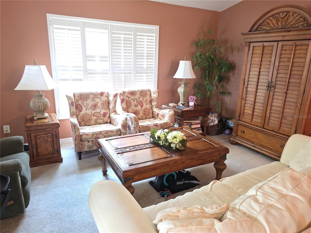 A living room features a wooden coffee table, two patterned armchairs, and a large armoire — 11442 TURTLE DOVE PLACE, NEW PORT RICHEY, FL