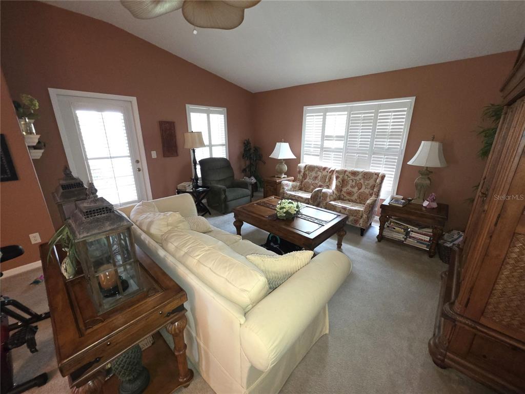 A living room features a white sofa, patterned armchairs, a wooden coffee table, and shutters — 11442 TURTLE DOVE PLACE, NEW PORT RICHEY, FL