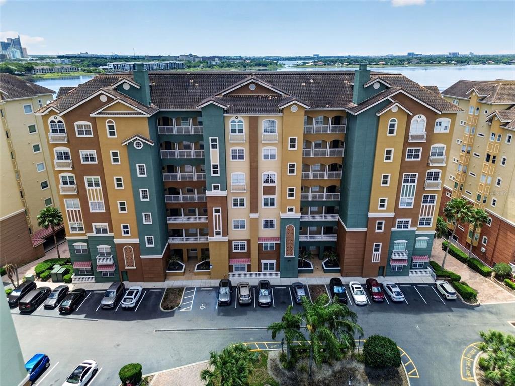 An aerial view shows a multi-story apartment building with a parking lot in front — 8749 THE ESPLANADE UNIT 18, ORLANDO, FL