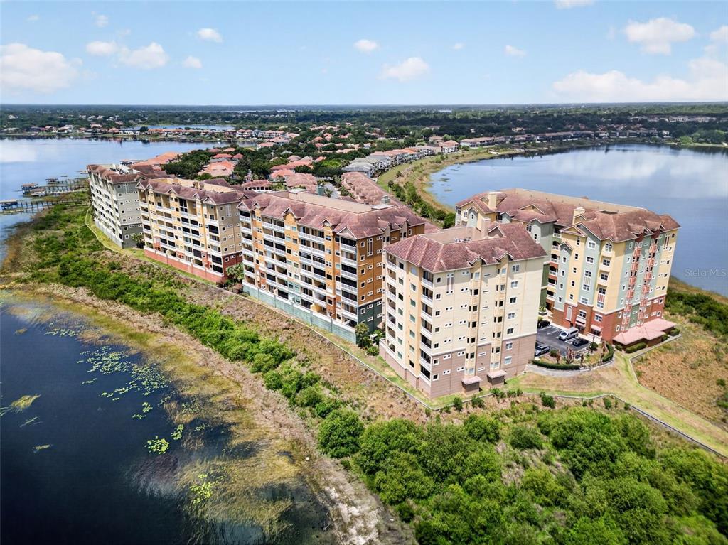 An aerial view of a large multi-story apartment complex situated along a lake — 8749 THE ESPLANADE UNIT 18, ORLANDO, FL