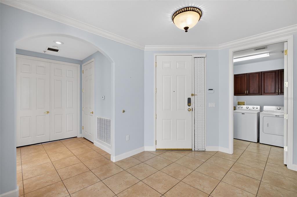 A tiled entryway features a white front door, a laundry room, and two closet doors — 8749 THE ESPLANADE UNIT 18, ORLANDO, FL