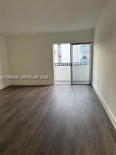 An empty room with dark wood-look flooring and a sliding glass door leading to a balcony — 2460 SW 18th Ave # 1211, Miami FL 33145, MIAMI, FL