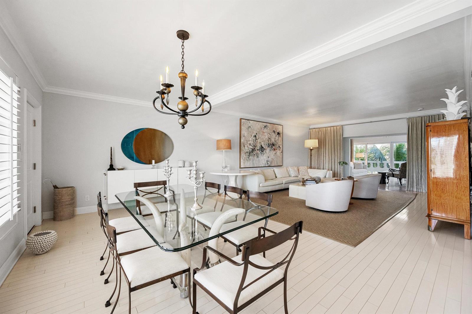 A dining area with a glass table and chandelier opens into a bright living room — 300 S Ocean Boulevard # 4f, Palm Beach FL 33480, PALM BEACH, FL