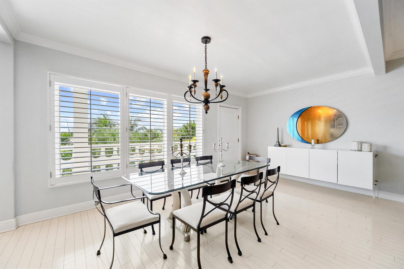 A dining room features a glass table, metal chairs, a chandelier, and white plantation shutters — 300 S Ocean Boulevard # 4f, Palm Beach FL 33480, PALM BEACH, FL