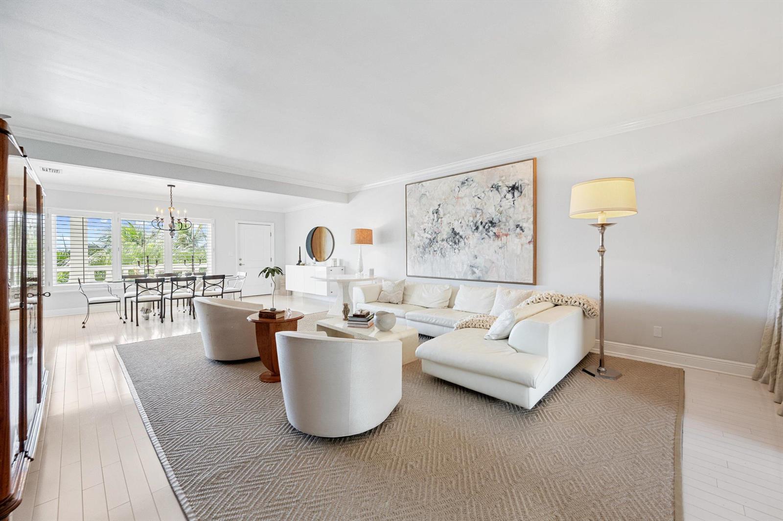 A bright living room features white furniture, a large abstract painting, and a textured rug — 300 S Ocean Boulevard # 4f, Palm Beach FL 33480, PALM BEACH, FL
