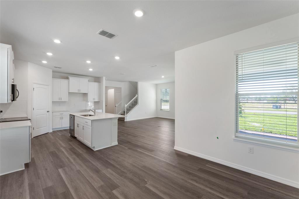 An open-concept kitchen and living area features white cabinets, a center island, and wood-look flooring — 12032 SHINE VIEW LANE, WINTER GARDEN, FL