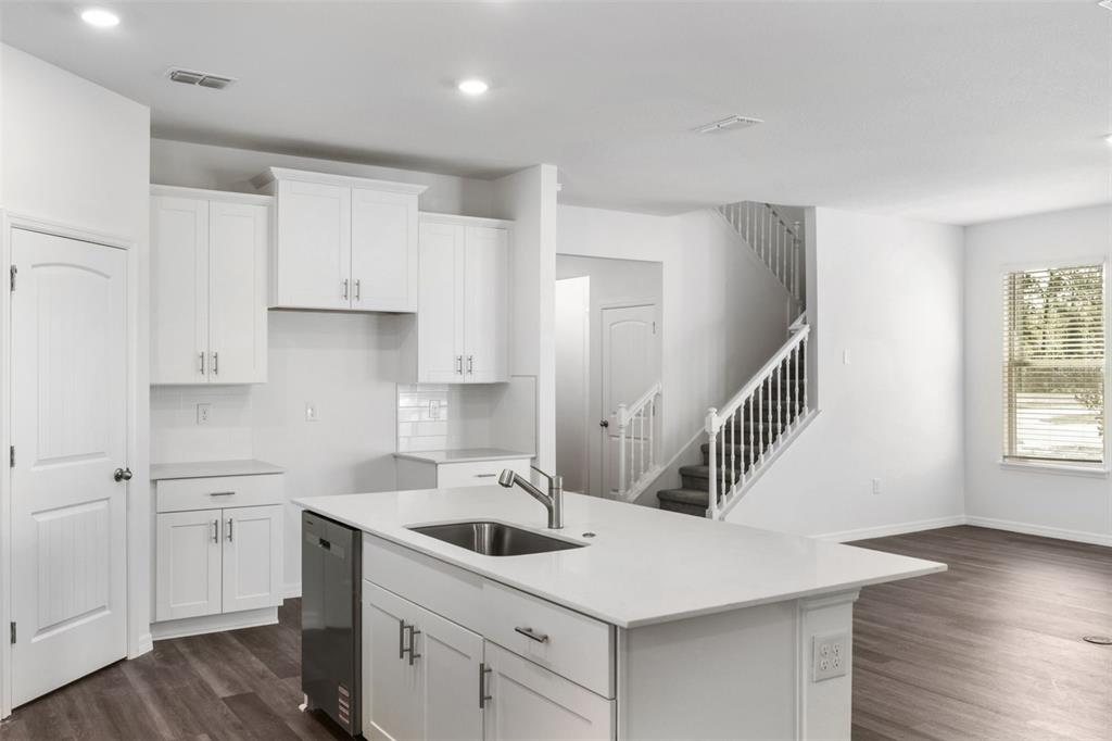 A kitchen with white cabinets, a central island with a sink, and an adjacent staircase — 12032 SHINE VIEW LANE, WINTER GARDEN, FL