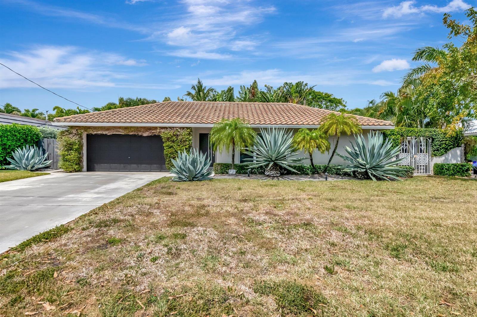 A single-story house with a tile roof, dark garage door, and large agave plants — 855 Berkeley Street, Boca Raton FL 33487, BOCA RATON, FL