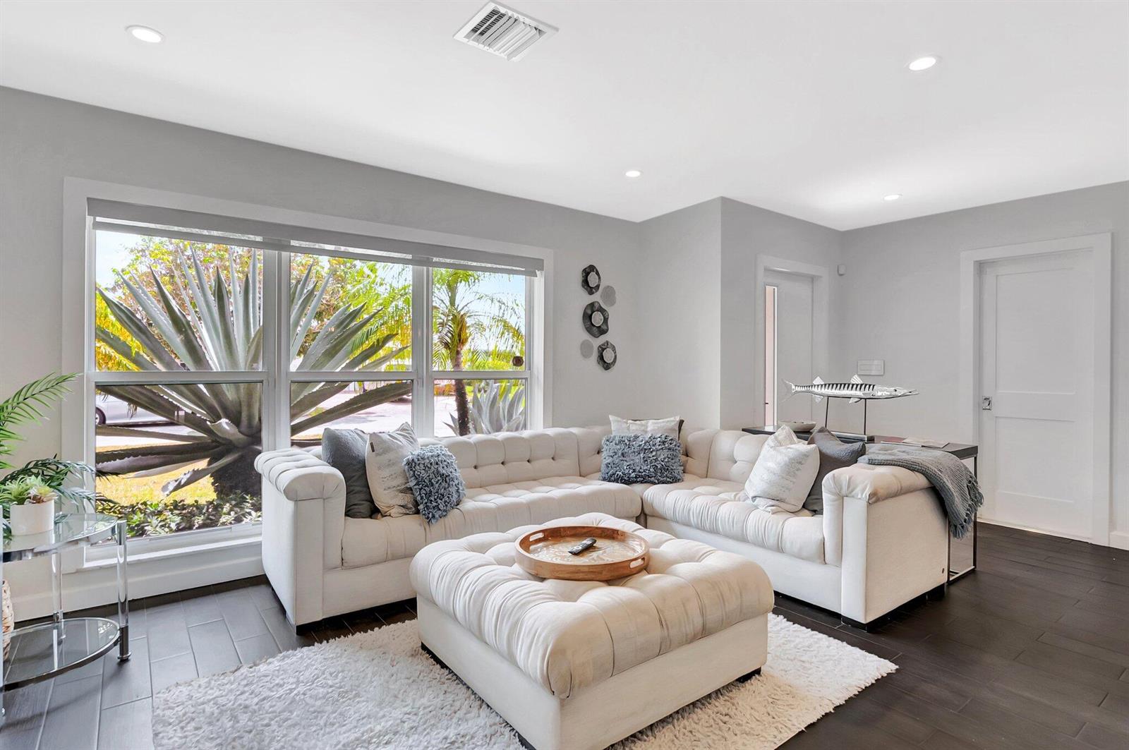 A living room features a white tufted sectional, a matching ottoman, and large windows — 855 Berkeley Street, Boca Raton FL 33487, BOCA RATON, FL