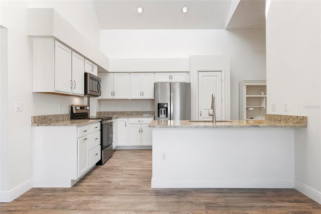 A kitchen with white cabinets, granite countertops, stainless steel appliances, and wood-look flooring — 3 INLETS BOULEVARD UNIT 3, NOKOMIS, FL