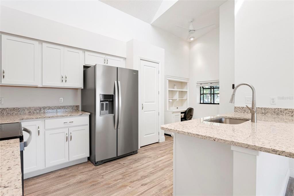 A kitchen features white cabinets, granite countertops, stainless steel appliances, and a small built-in desk — 3 INLETS BOULEVARD UNIT 3, NOKOMIS, FL