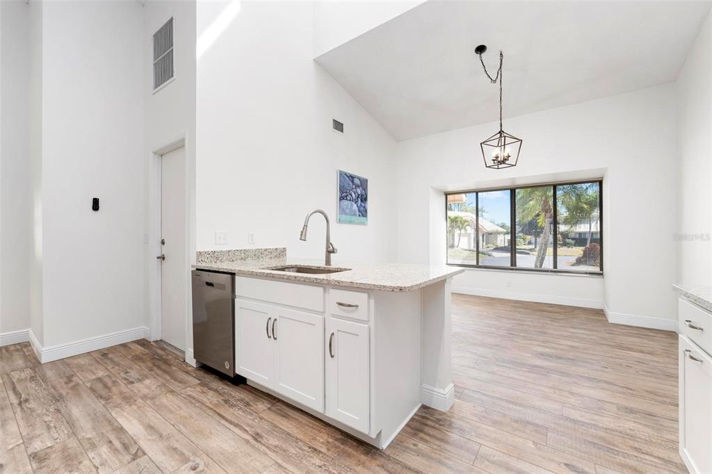 A kitchen island with a stainless steel dishwasher and sink sits in a bright room — 3 INLETS BOULEVARD UNIT 3, NOKOMIS, FL