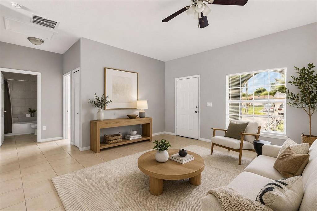 A living room with light tile floors, a beige area rug, and a wooden coffee table — 677 ROYALTY COURT, KISSIMMEE, FL