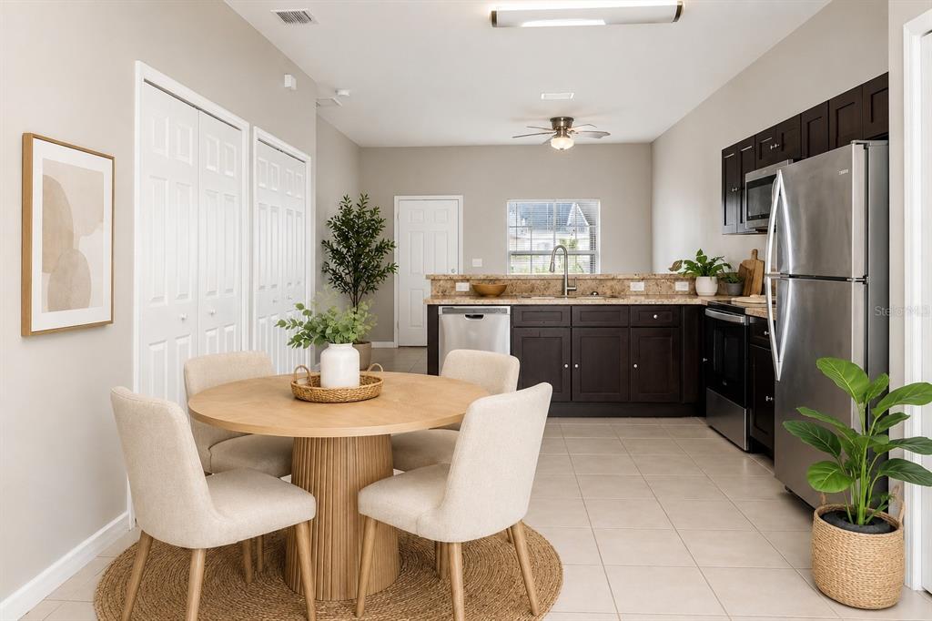 A dining area with a round table sits adjacent to a kitchen with dark cabinets — 677 ROYALTY COURT, KISSIMMEE, FL