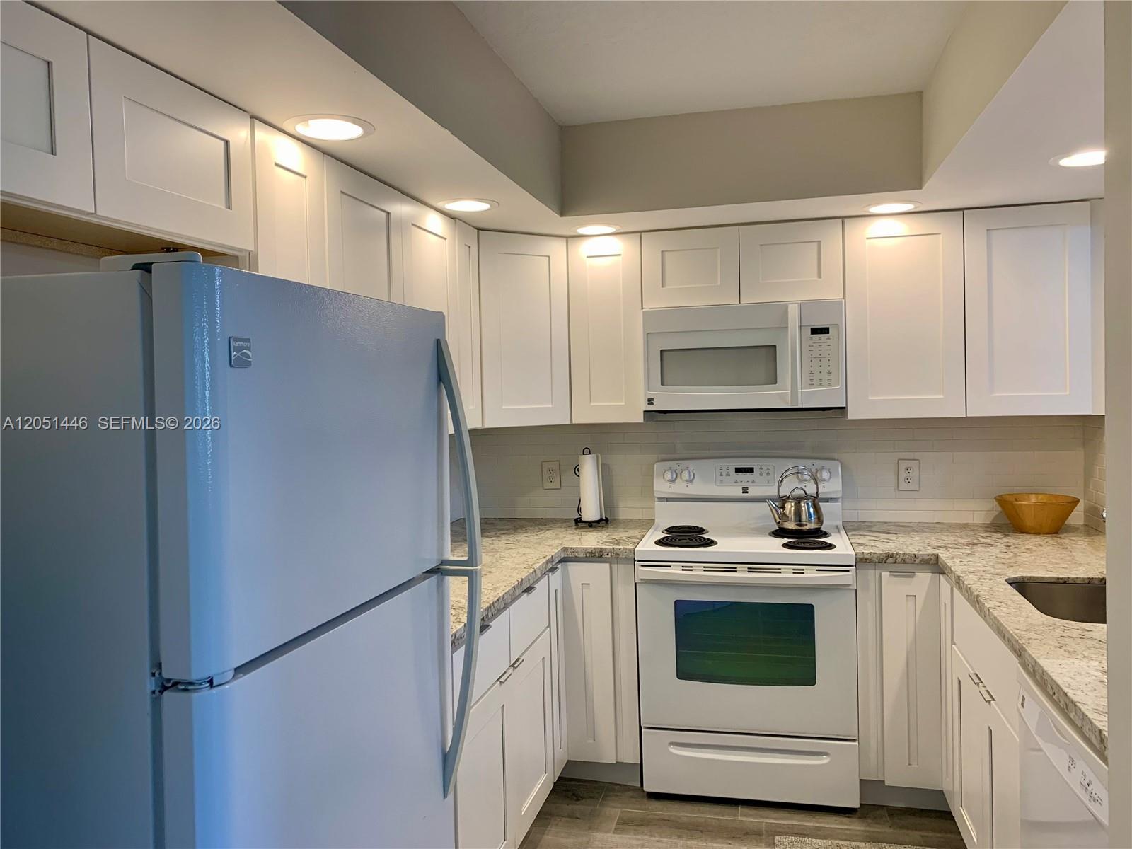 A kitchen features white cabinets, granite countertops, a white refrigerator, and a white electric range — PEMBROKE PINES, FL