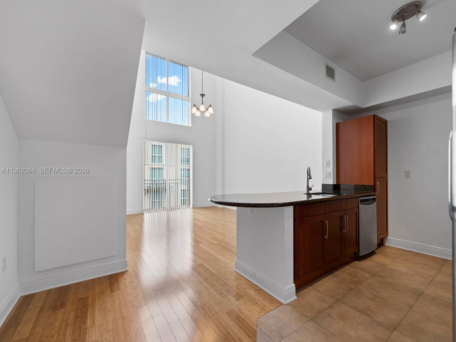 A kitchen with dark wood cabinets and a breakfast bar overlooks a double-height living area — 7265 SW 89th St # A520, Miami FL 33156, MIAMI, FL