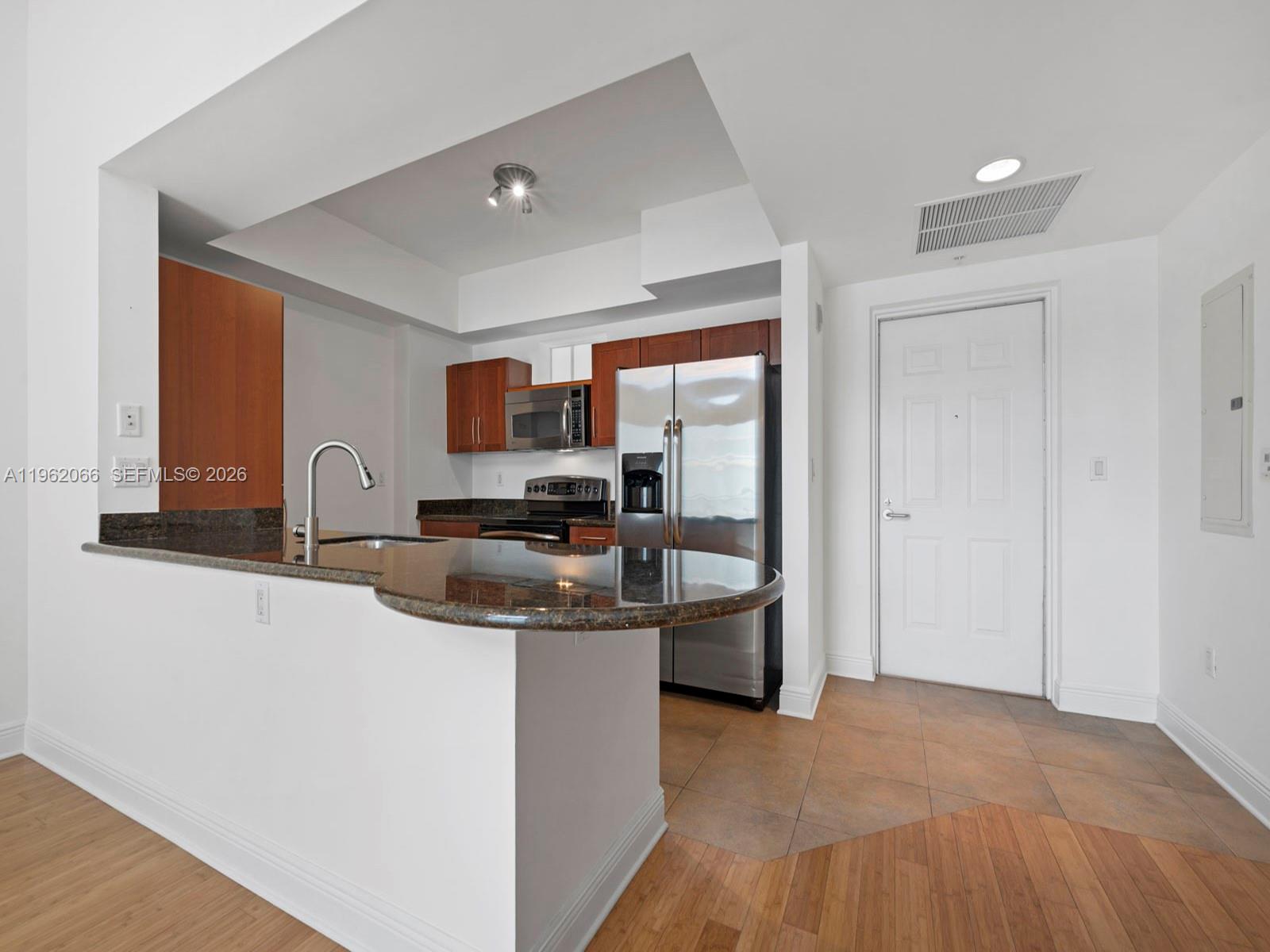 A kitchen features wood cabinets, stainless steel appliances, a granite countertop, and tile flooring — 7265 SW 89th St # A520, Miami FL 33156, MIAMI, FL