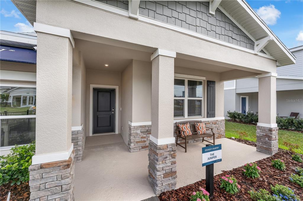 The exterior of a house features a covered porch with stone columns and a bench — 3700 ROLLING RIDGE BEND, DAVENPORT, FL