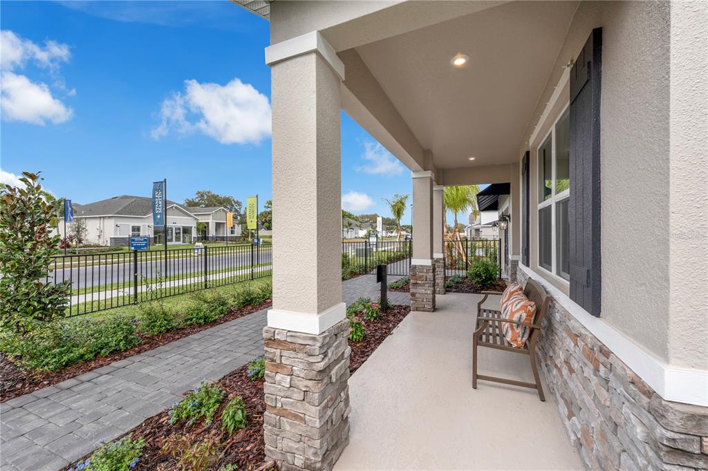 A covered front porch features stone-based columns, a bench, and a paved walkway — 3700 ROLLING RIDGE BEND, DAVENPORT, FL